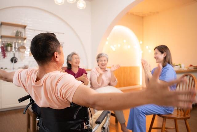 Group of elderly and senior man in wheelchair with nurse at nursing home Play a fun game of hitting each other's hands. Elderly people in nursing home concept